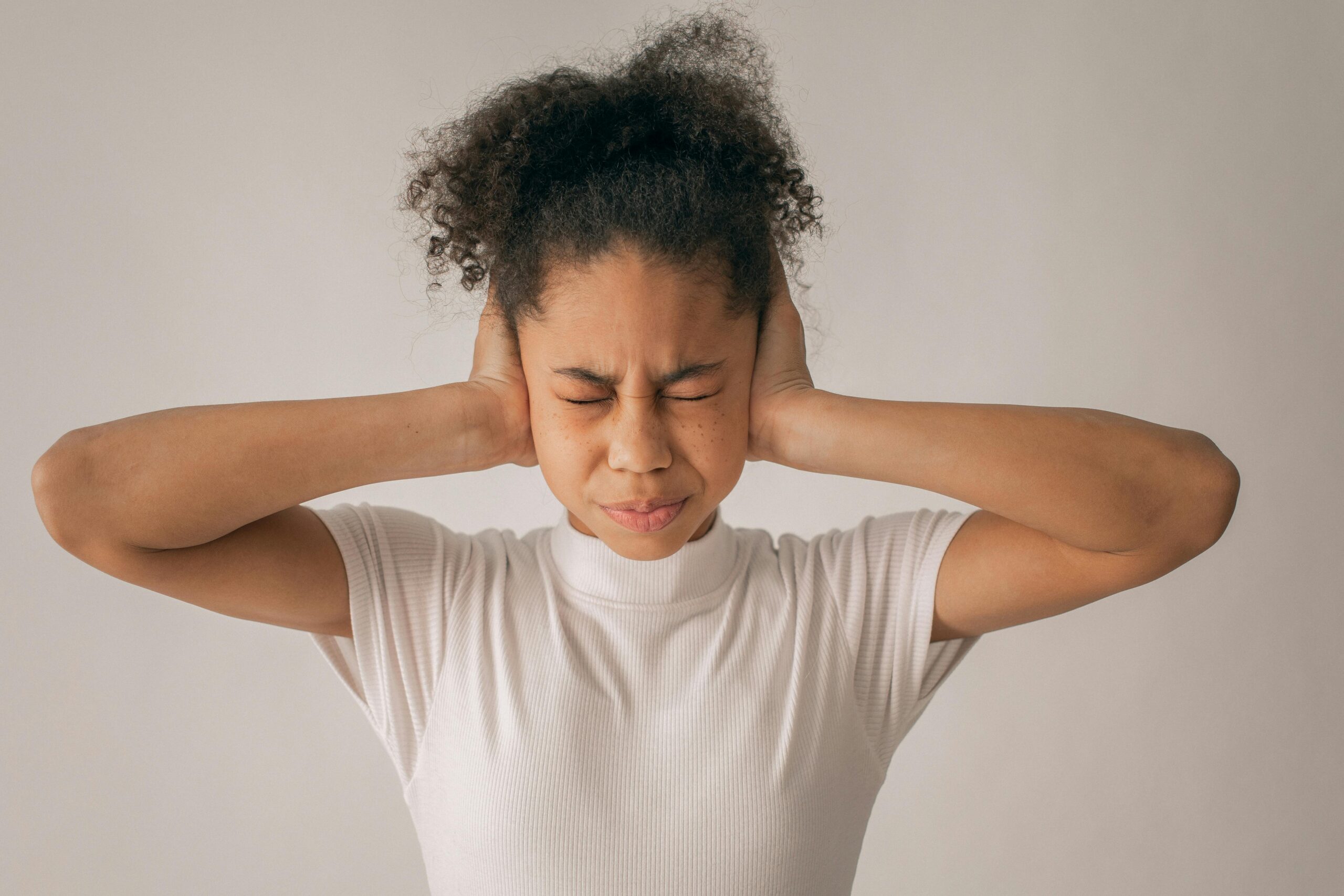 Stressed black girl covering ears
